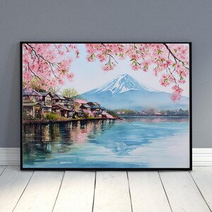 Peut inclure: Peinture &agrave; l'aquarelle d'un paysage japonais avec le Mont Fuji, un lac et des maisons traditionnelles. Des fleurs de cerisier roses encadrent la sc&egrave;ne, avec des reflets dans l'eau. L'&oelig;uvre est encadr&eacute;e en noir.