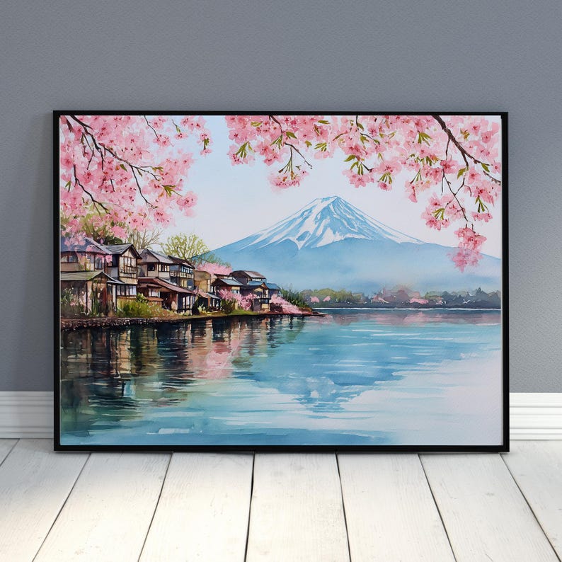 Peut inclure: Peinture &agrave; l'aquarelle d'un paysage japonais avec le Mont Fuji, un lac et des maisons traditionnelles. Des fleurs de cerisier roses encadrent la sc&egrave;ne, avec des reflets dans l'eau. L'&oelig;uvre est encadr&eacute;e en noir.