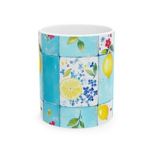 May include: A white ceramic mug with a repeating pattern of blue squares. Each square features a watercolor design of lemons, flowers, and leaves. The mug has a bright, cheerful aesthetic.