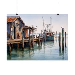 May include: Watercolor print of a coastal scene featuring a weathered wooden shack and pier. A teal fishing boat is docked nearby. Seagulls perch on the pier and pilings. The water reflects the sky and structures, creating a serene, nautical theme.