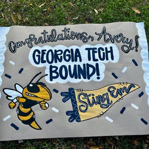May include: A brown banner with the text "Congratulations, Avery!" and "GEORGIA TECH BOUND!" in black and white. A yellow and black cartoon hornet and a yellow pennant that says "Sting Em" are also featured.