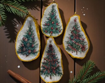 May include: Four Christmas tree ornaments in the shape of oyster shells. Each shell has a gold rim and a painted Christmas tree design. The trees are decorated with red ornaments and ribbons. The ornaments are displayed on a wooden surface with pine needles and a cinnamon stick.