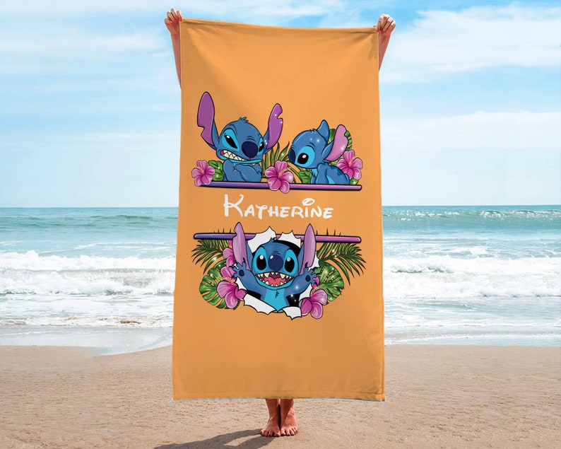 May include: A yellow beach towel with a personalized name "Katherine" and three blue Stitch characters from the Disney movie Lilo & Stitch. The characters are surrounded by pink flowers and green leaves.
