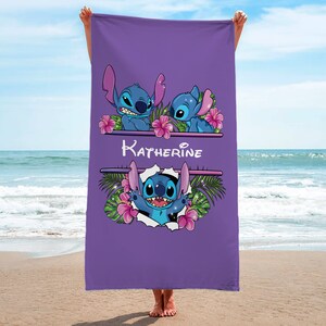 May include: Purple beach towel with a personalized name "Katherine" and three Stitch characters from Lilo & Stitch. The Stitch characters are surrounded by tropical flowers and leaves.