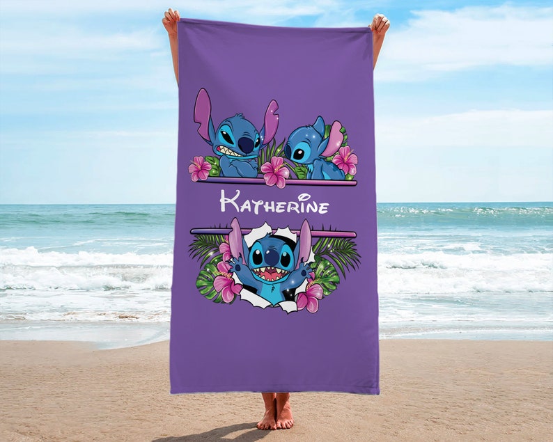 May include: Purple beach towel with a personalized name "Katherine" and three Stitch characters from Lilo & Stitch. The Stitch characters are surrounded by tropical flowers and leaves.