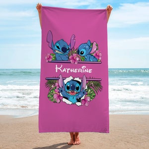 May include: Pink beach towel with a blue Stitch character from Disney's Lilo & Stitch. The towel has a floral design and the name "Katherine" printed on it.