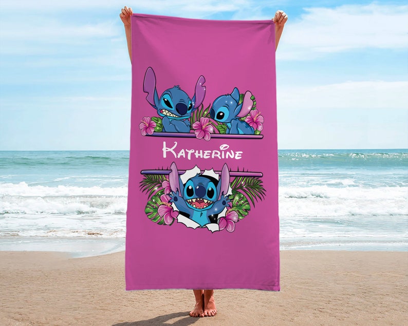 May include: Pink beach towel with a blue Stitch character from Disney's Lilo & Stitch. The towel has a floral design and the name "Katherine" printed on it.