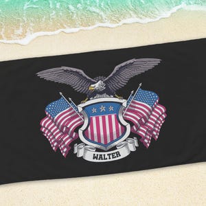 May include: Black beach towel featuring a patriotic design. The design includes a detailed illustration of an eagle with outstretched wings, a shield with red and white stripes, and American flags. The name "WALTER" is displayed on a banner.