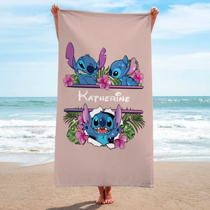 May include: A pink beach towel with a design featuring Stitch from Lilo & Stitch. The towel has a floral design and the name "Katherine" written on it.
