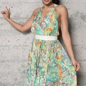 May include: A green and white maxi dress with a floral print and a white belt. The dress has a V-neckline and a halter strap.