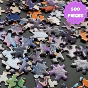 May include: A 500 piece jigsaw puzzle with various colored puzzle pieces scattered on a black surface. The puzzle pieces have a glossy finish and feature a cartoon-like design.