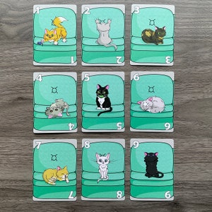 May include: Nine green cards with a number on each card. Each card has a picture of a cat sitting in a chair. The cats are different colors and have different poses.