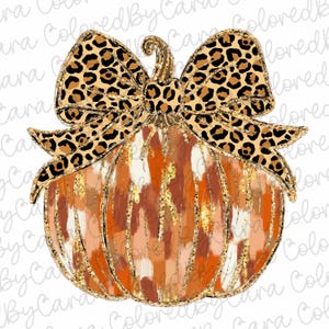 Puede incluir: Una calabaza marrón y naranja con un acabado de purpurina dorada y un gran lazo de estampado de leopardo. La calabaza tiene un patrón abstracto blanco y marrón.