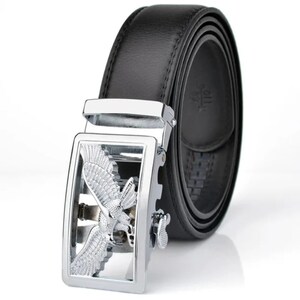 May include: A black leather belt with a silver buckle featuring a detailed eagle design. The buckle has a ratcheting mechanism for adjusting the belt length.