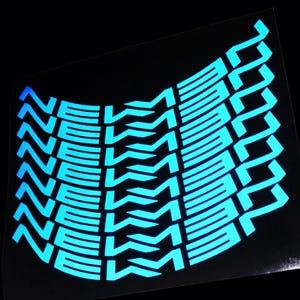 May include: A sheet of stickers with a repeating design in bright blue. The design features the word "NEW" stacked vertically with a stylized "2" on the right side. The stickers have a glossy finish against a black background.