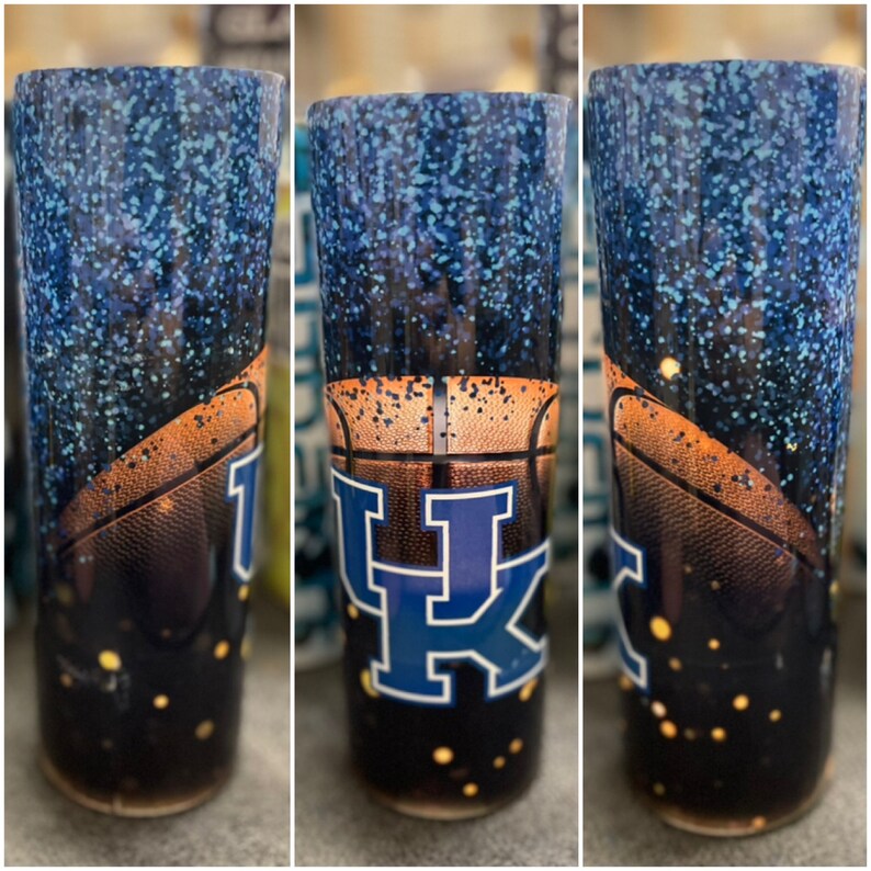 May include: A blue and black tumbler with a basketball and the letters "UK" in blue with white outlines. The tumbler is covered in blue glitter.