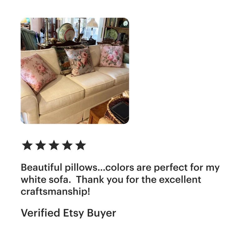 May include: A cream-coloured sofa with four decorative throw cushions. The cushions feature floral patterns in shades of pink, green, and grey. The sofa is in a well-lit room with other decorative items.
