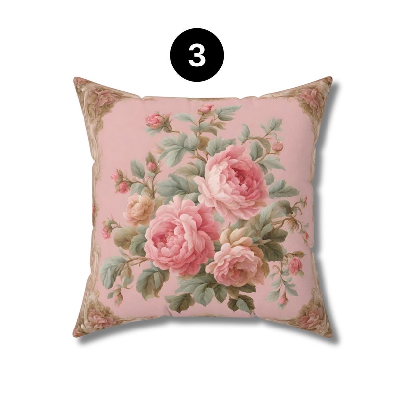 May include: Square cushion with a floral design. The cushion has a pink background with a bouquet of pink and cream roses and green leaves. The corners have a decorative border and the number "3" is in a black circle.