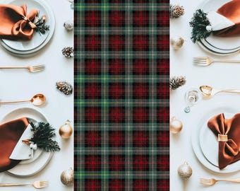 May include: Overhead shot of a festive table setting with white plates, copper-colored napkins, gold cutlery, and decorative pinecones and ornaments. A central plaid pattern in red, green, and black adds a holiday touch.