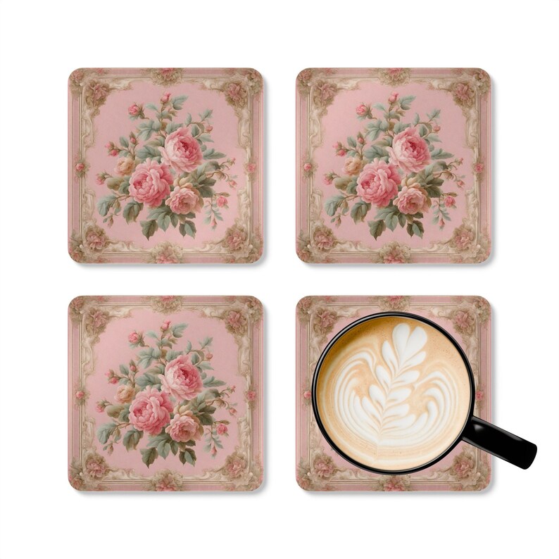May include: A set of four square coasters featuring a pink background with a central bouquet of pink roses and green leaves, framed by an ornate beige border. One coaster supports a black mug filled with coffee featuring white latte art.