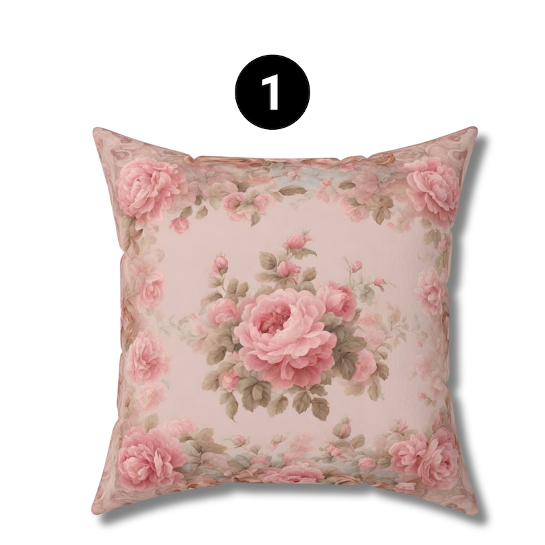 May include: Square cushion with a floral design. The cushion has a pale pink base, adorned with a pattern of pink roses and green foliage. The roses are fully open, with smaller buds and leaves surrounding them.