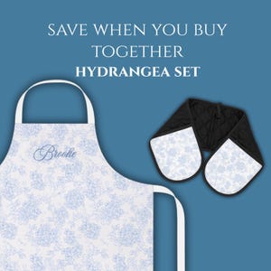 Puede incluir: Un delantal blanco y un juego de manoplas dobles con un patr&oacute;n floral de hortensias azul claro. El delantal muestra el nombre Brooke en letra cursiva azul. El texto superior dice: SAVE WHEN YOU BUY TOGETHER HYDRANGEA SET.