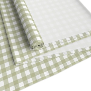 May include: A green and white checkered tablecloth is rolled up. The tablecloth has a white border with a stitched edge.