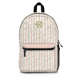 May include: A backpack featuring a vertical striped pattern in light pink and white, decorated with a repeating floral vine print. The front pocket is solid light pink with a black zipper. A circular monogram with the letters ARD is centered.