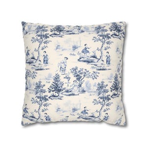 May include: A square throw pillow featuring a cream-colored background with a repeating blue toile de jouy pattern. The design depicts various figures in period clothing, trees, and landscape elements distributed across the fabric surface.