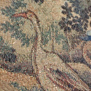 May include: Close-up of a woven tapestry with a detailed landscape design. The tapestry features a color palette of beige, teal, and dark blue, depicting trees and foliage. The texture of the weave is visible, adding depth to the artwork.