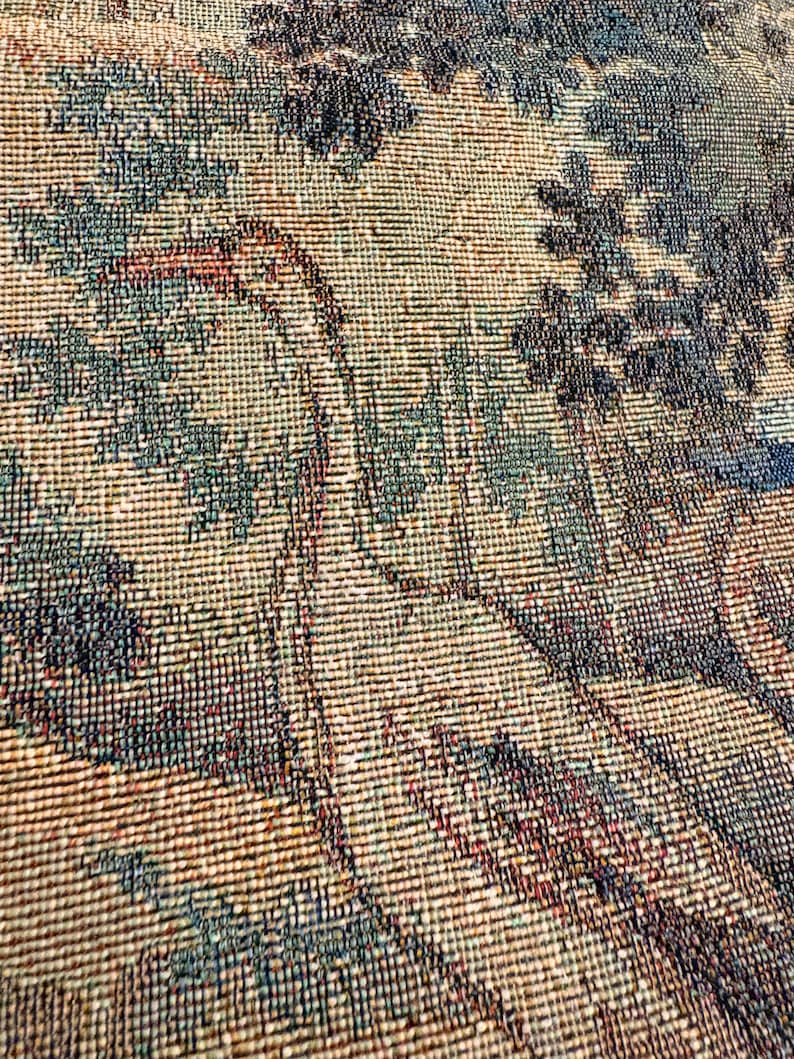 May include: Close-up of a woven tapestry with a detailed landscape design. The tapestry features a color palette of beige, teal, and dark blue, depicting trees and foliage. The texture of the weave is visible, adding depth to the artwork.