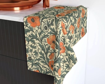 May include: A rectangular hand towel featuring a repeating botanical pattern of orange poppy flowers and dark sage green foliage on a cream-colored background. The fabric is draped over the edge of a dark cabinet with a copper sink fixture above.