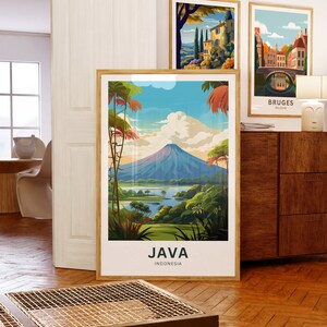 May include: Three framed art prints. The largest features a landscape of Java, Indonesia, with a volcano, lush greenery, and the text "JAVA INDONESIA." Other prints depict European scenes. All are in wooden frames, displayed on a wooden cabinet.