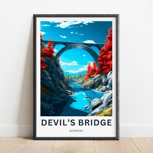 May include: A framed print of a painting depicting a stone bridge over a river in a forest. The bridge is arched and has a blue sky above it. The river is blue and the forest is green. The trees on the sides of the bridge are red. The text "DEVIL'S BRIDGE GERMANY" is at the bottom of the print.
