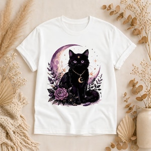 May include: White t-shirt featuring a black cat with a crescent moon and floral design. The cat has a gold necklace with a crescent moon pendant. The design includes purple roses and stars.