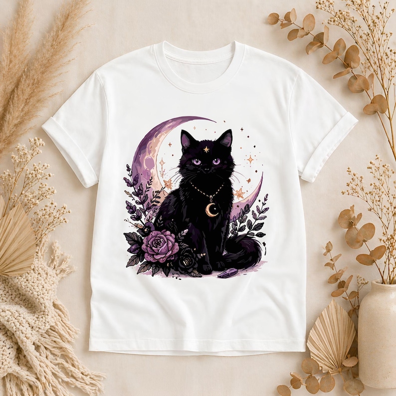 May include: White t-shirt featuring a black cat with a crescent moon and floral design. The cat has a gold necklace with a crescent moon pendant. The design includes purple roses and stars.