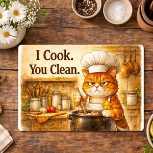 May include: Rectangular kitchen mat with a watercolor illustration of an orange tabby cat wearing a chef's hat and apron, stirring a pot. Text reads "I Cook. You Clean."