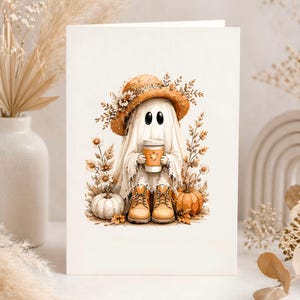 May include: A greeting card featuring a whimsical ghost character. The ghost wears a straw hat adorned with flowers and holds a coffee cup. The illustration includes pumpkins, boots, and fall foliage, creating a seasonal theme.