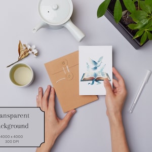 May include: A white card with a watercolor illustration of two doves flying out of an open book. The book is blue and gold with a blue ribbon. The card is being held by a person's hands.