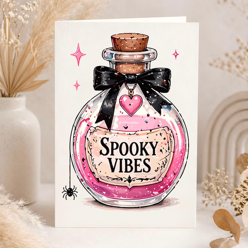 Może przedstawiać: Kartka okolicznościowa z kresk&oacute;wkową ilustracją butelki z miksturą z r&oacute;żowym płynem i napisem "Spooky Vibes". Butelka ma czarną kokardę, korek i r&oacute;żową zawieszkę w kształcie serca. Mały pająk wisi poniżej.