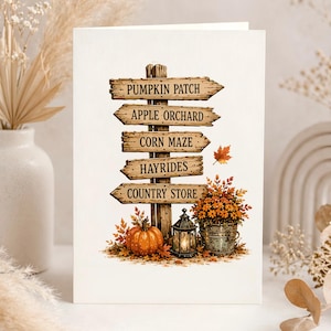 Puede incluir: Una tarjeta de felicitaci&oacute;n con un poste de madera y cinco flechas direccionales que dicen PUMPKIN PATCH, APPLE ORCHARD, CORN MAZE, HAYRIDES y COUNTRY STORE. Debajo hay una calabaza naranja, un farol negro y un cubo con flores naranjas.