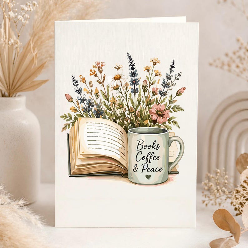 K&ouml;nnte beinhalten: Eine Gru&szlig;karte mit einer Illustration eines aufgeschlagenen Buches und einer hellgr&uuml;nen Tasse mit dem Text Books Coffee & Peace und einem kleinen Herz. Hinter dem Buch und der Tasse befindet sich ein buntes Arrangement aus Wildblumen in Rosa, Blau und Gelb.