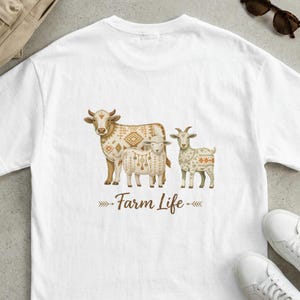 May include: White t-shirt featuring a cow, sheep, and goat with patterned designs. The words "Farm Life" are printed below the animals. The shirt is a casual wear item.