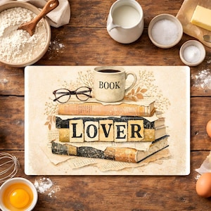 May include: A decorative cutting board with a stack of books, a coffee mug with the word "BOOK", and eyeglasses. The word "LOVER" is spelled out on the books. Baking ingredients and tools surround the board.