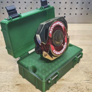 Puede incluir: Una moneda ZyuRanger Kyoryu Sentai dorada, roja y negra en un estuche verde. La moneda tiene el texto "ZyuRanger" y "Kyoryu Sentai" en blanco. El estuche verde est&aacute; abierto, revelando la moneda en su interior.