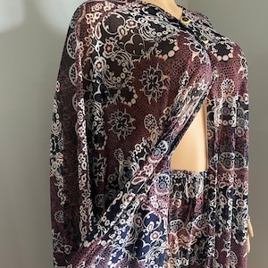 May include: A sheer, long-sleeved dress with a floral print in shades of black, white, and red. The dress has a V-neckline and a button closure at the front.