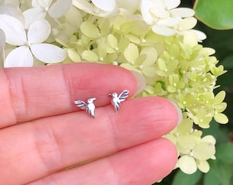 May include: A pair of silver hummingbird earrings. The earrings are small and delicate, and they are perfect for adding a touch of whimsy to any outfit.