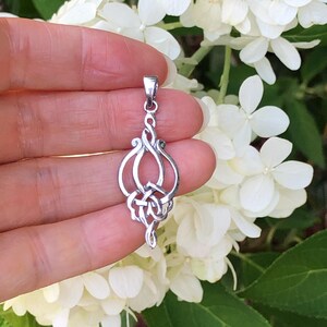 May include: A silver pendant with a Celtic knot design. The pendant is intricate and detailed, with a swirling pattern of knots.