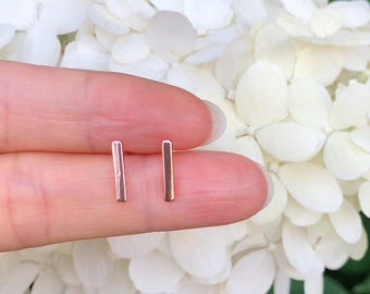 May include: A pair of silver bar stud earrings. The earrings are small and simple, and they are perfect for everyday wear.