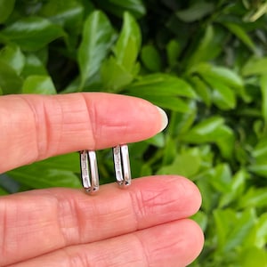May include: A pair of silver hoop earrings with small clear stones set in the metal.